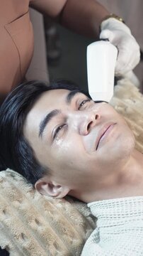 A young male client receiving a 2D HIFU facial session in an aesthetic clinic for noninvasive skin tightening and rejuvenation.v