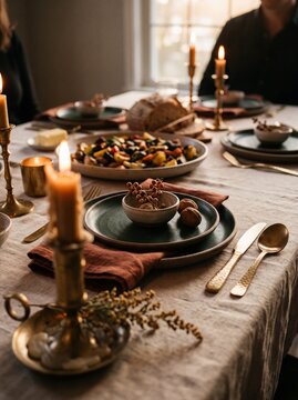 Cozy Thanksgiving or autumn dinner table setting with burning candles, delicious roasted vegetables, fresh bread, and elegant tableware in warm lighting