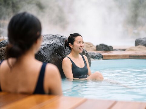 Young Asian woman relaxing in outdoor hot spring thermal pool at spa resort enjoying wellness trip