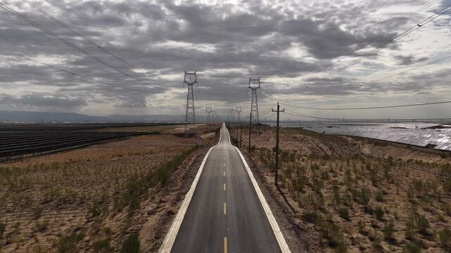 High-voltage Power Transmission Towers and Solar Farm Along Asphalt Road in Gobi Desert, Northwest China