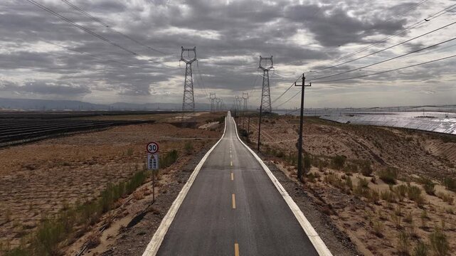 High-voltage Power Transmission Towers and Solar Farm Along Asphalt Road in Gobi Desert, Northwest China
