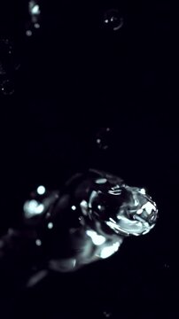 Abstract slow motion water droplets and flowing splash isolated on a black backdrop.
