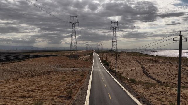 High-voltage Power Transmission Towers and Solar Farm Along Asphalt Road in Gobi Desert, Northwest China