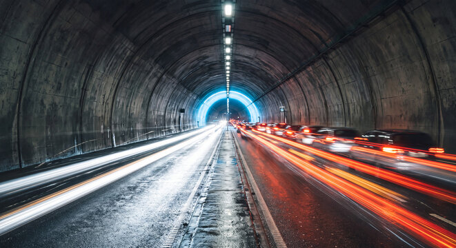 Tunnel roadway with blurred vehicle light trails showcases symmetrical perspective