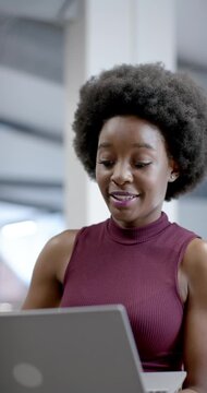 Vertical video: African American woman reading laptop reacting to screen, smiling, typing in office