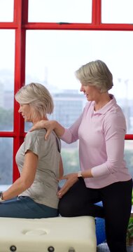 Vertical video: Therapist placing hands on woman, guiding thoracic extension at table for posture