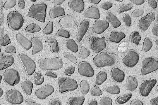 A textured surface made of rounded stones embedded in smooth concrete.