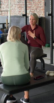 Vertical video: Female coach speaking and showing breathing posture on bench, client reaching phone