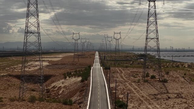 High-voltage Power Transmission Towers and Solar Farm Along Asphalt Road in Gobi Desert, Northwest China