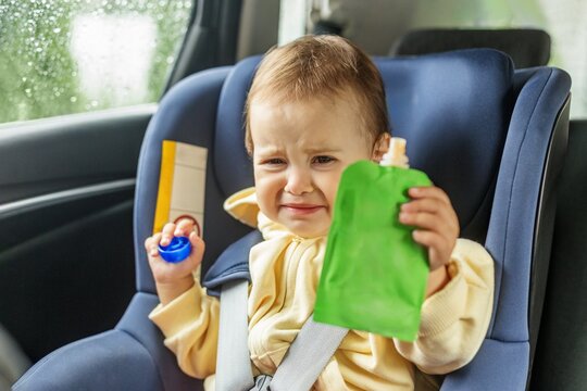 Crying Toddler Refusing Food While Secured in Car Seat During Rainy Car Ride