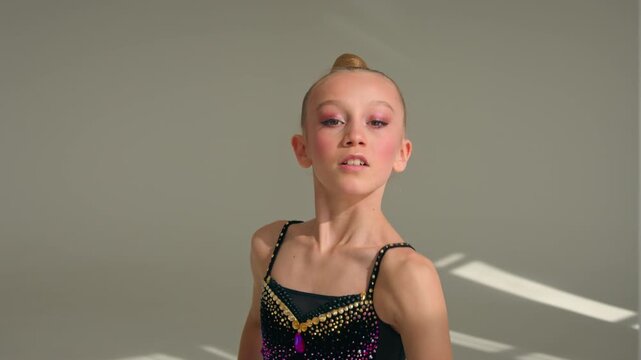 Focused Caucasian little girl gymnast dancer spinning gymnastic tape in dance studio class talented child skilled athlete schoolgirl kid ballerina training sport choreography dancing exercise indoor