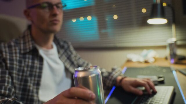 Young adult Caucasian man playing video games on multiple screens late at night and drinking soda. Clip is perfect for commercial campaigns addressing screen addiction, esports, or tech overuse