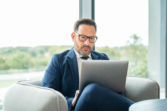 Dedicated businessman using a laptop while sitting in a modern corporate lounge. Focusing on tasks related to finance. Legal advising. And accounting