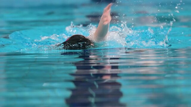 Swimmer child swims backstroke swimming style in the pool. Slow motion.