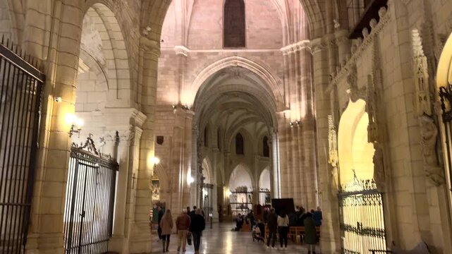 Interior view of the Cathedral of Murcia with gothic arches, stone vaults and visitors walking along the nave
