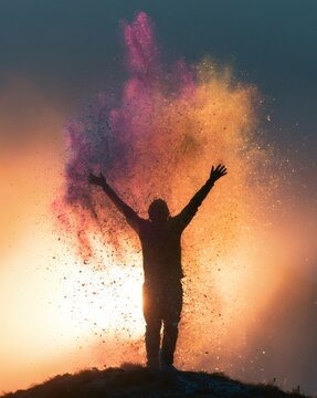 Person silhouette celebrating with colorful powder explosion