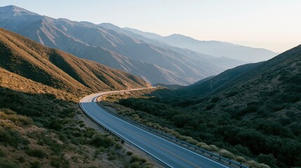 Obraz premium The winding mountain road curling through sunlit valleys and distant peaks