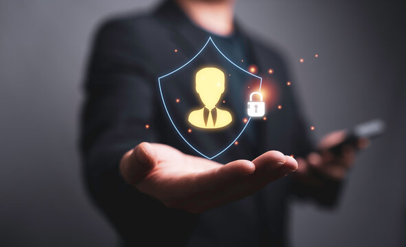 Businessman holding digital shield with user and lock icons for data privacy protection, cybersecurity, identity security, access control, personal information safety and secure digital services.