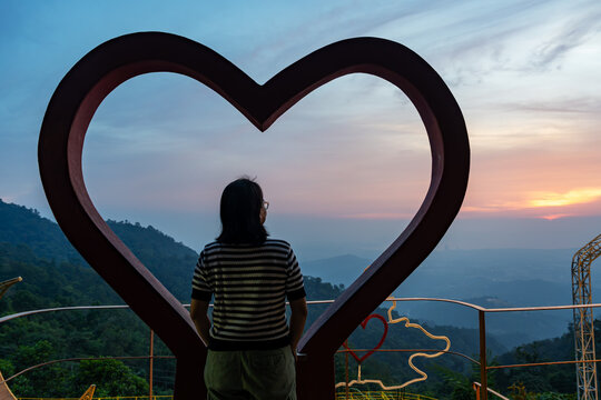 Heart shape surround woman looking over sunset in Kokol Hills Kota Kinabalu Sabah Borneo Malaysia