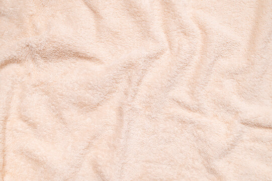 Soft terry towel texture fills frame in closeup, showing plush cotton fibers, gentle folds and open space for text, creating neutral textile background for wellness, retail and lifestyle design.