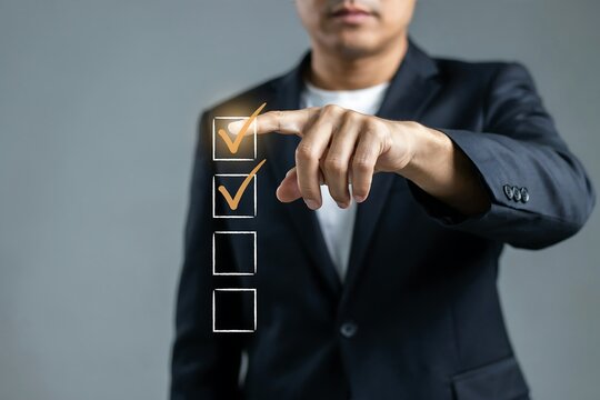 Businessman in a suit selecting a checkbox on a digital interface against a grey background