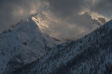 Dramatic mountain peak under winter clouds with sunlight hitting the snow. High-contrast landscape ideal for travel and adventure themes. © marcodenaro
