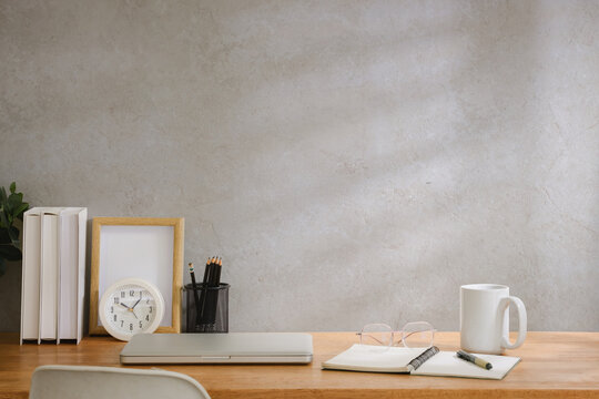 Clean modern desk setup with laptop, stationery, clock, coffee cup and indoor plant in soft natural light, ideal for remote work them