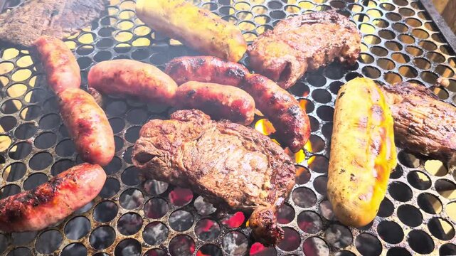 Juicy beef steaks and pork sausages sizzling on a hot charcoal grill. Close-up of a traditional barbecue with rising smoke and glowing embers.