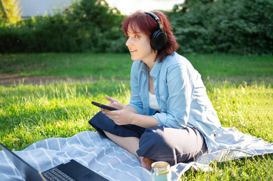 Happy digital nomad enjoying music and sunshine during work pause outdoors.