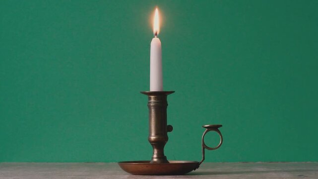 place a burning candle in an antique candlestick on the table