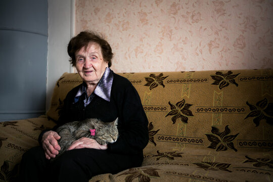Senior woman sitting on a sofa with a sleeping cat on her lap at home
