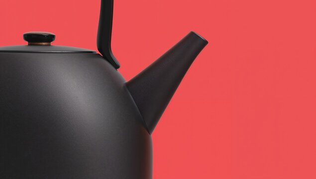Close up of a matte black kettle with a spout and handle resembling a startled face against a vibrant red background, showcasing unique design features and modern aesthetics