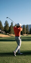 Obraz premium Male golfer swinging on a green fairway golf course in orange shirt for sports background and outdoor banner design