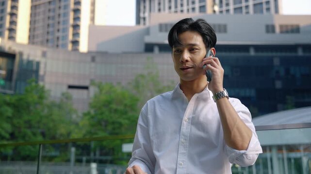 Businessman having a phone conversation outdoors in a modern city environment, representing professional communication, business networking, and mobile connectivity.
