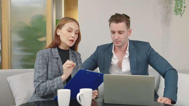 Business professionals discussing documents and reviewing information with a laptop in a modern office, representing consultation, teamwork, planning, communication, and corporate collaboration.
