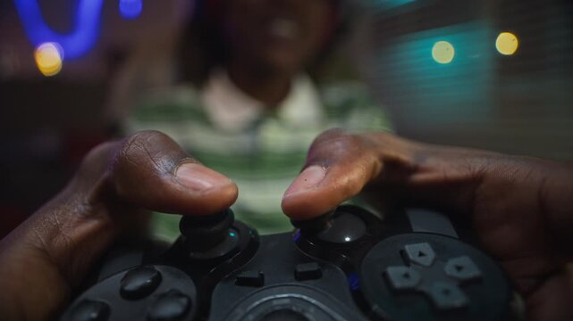 African American teenager playing video games, pressing buttons on controller in extreme close up. Clip is ideal for projects on gaming addiction, esports, or modern youth entertainment