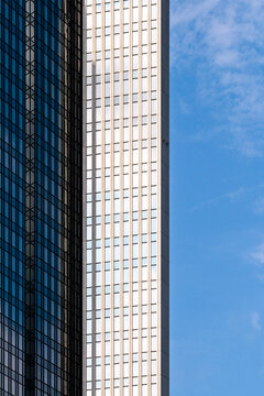 Blue sky opens beside a skyscraper as height is emphasized by vertical windows, while the facade carries modern office architecture through the urban frame.