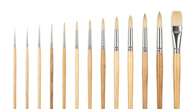 Set of thirteen artist paint brushes with wooden handles arranged by size on black background