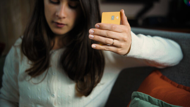 Young Latina woman holding her credit card at home while preparing to make an online purchase, focused on the payment process.