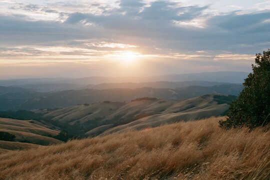 The Sunset Over Rolling Hills and Golden Grasslands at Distant Horizon