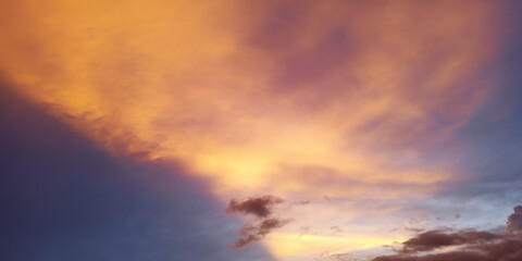 Fototapeta premium Dramatic sunset sky with vibrant orange and purple clouds over calm water horizon