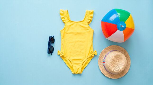 Yellow swimsuit with beach accessories on a blue background