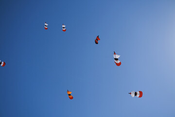 Fototapeta premium Colorful traditional Balinese kites flying in a blue sky with sunlit kite strings