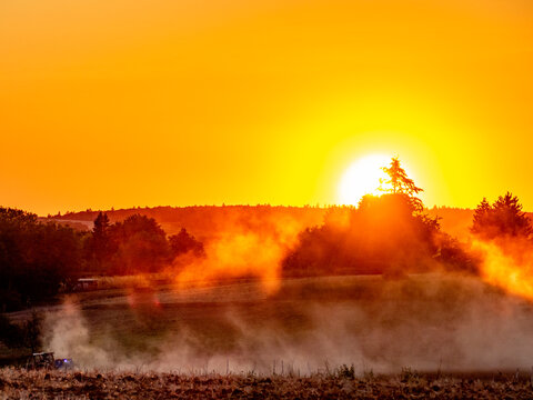 Traktor wirbelt Staub auf bei Sonnenuntergang