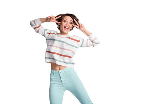 Photo of adorable sweet young lady wear striped sweater dancing showing v-sign isolated grey color background