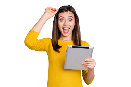 Portrait of lovely amazed cheerful girl holding in hands using tablet fast speed isolated over grey color background