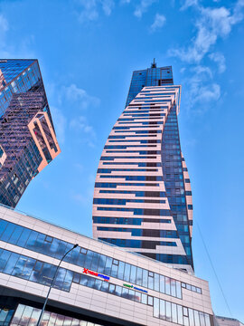 Rzeszow, Poland - Aug 11, 2026: Low angle view of a modern twisted high-rise tower with striped facade design against a blue sky with clouds in the city center