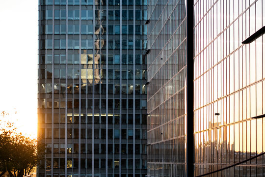 Sunset reaches La Defense, Paris, France, where glass office towers mirror warm light across the urban skyline, and each facade turns the architecture into reflection.