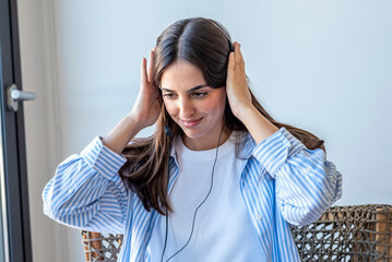 Fototapeta premium Young woman adjusting headset and smiling while working from home on a remote call or online meeting