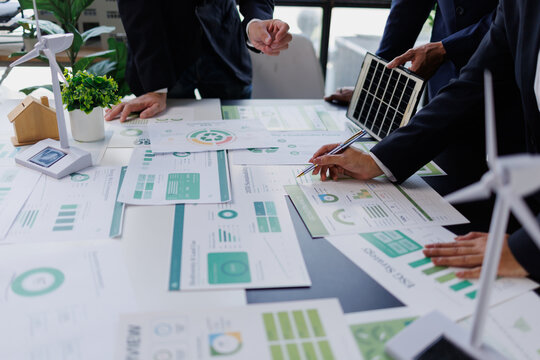 Business team analyzing esg strategy, discussing sustainability and renewable energy goals with green corporate reports